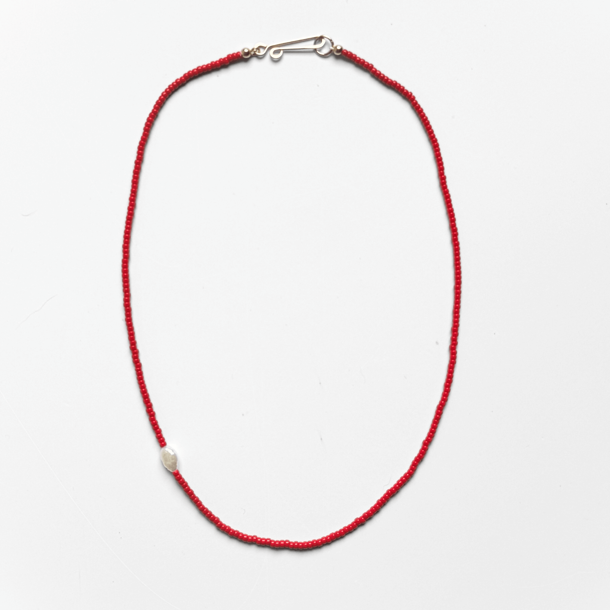 KHADI NECKLACE featuring red seed beads, a freshwater pearl, and gold-filled clasp, celebrating simplicity and beauty.