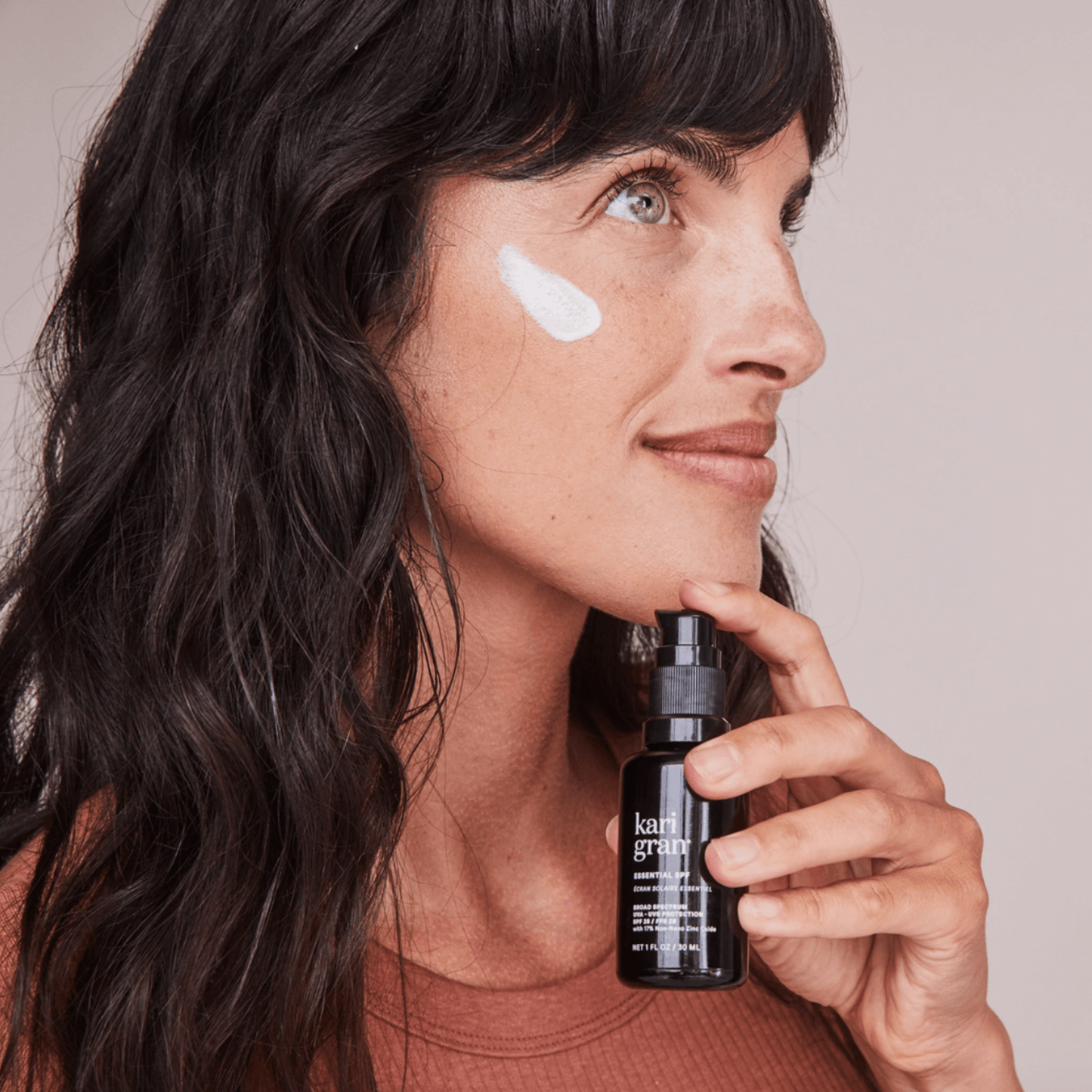 Model applying Kari Gran's Essential SPF 30 mineral sunscreen, showcasing non-white cast formula.