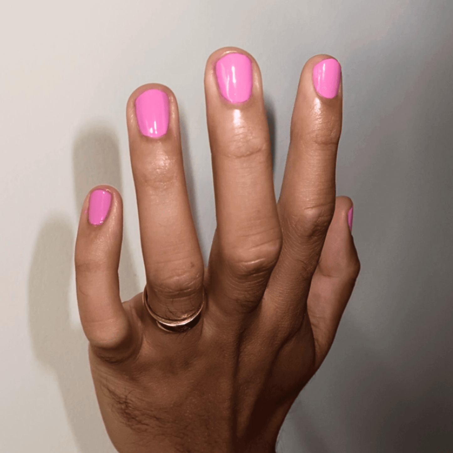 Hand with bubblegum pink nail polish, showcasing a vibrant, playful shade that's vegan and cruelty-free.