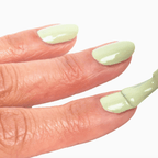 A hand applying sage green Forever Wear Chill Paint nail polish for a fresh, chip-resistant finish.