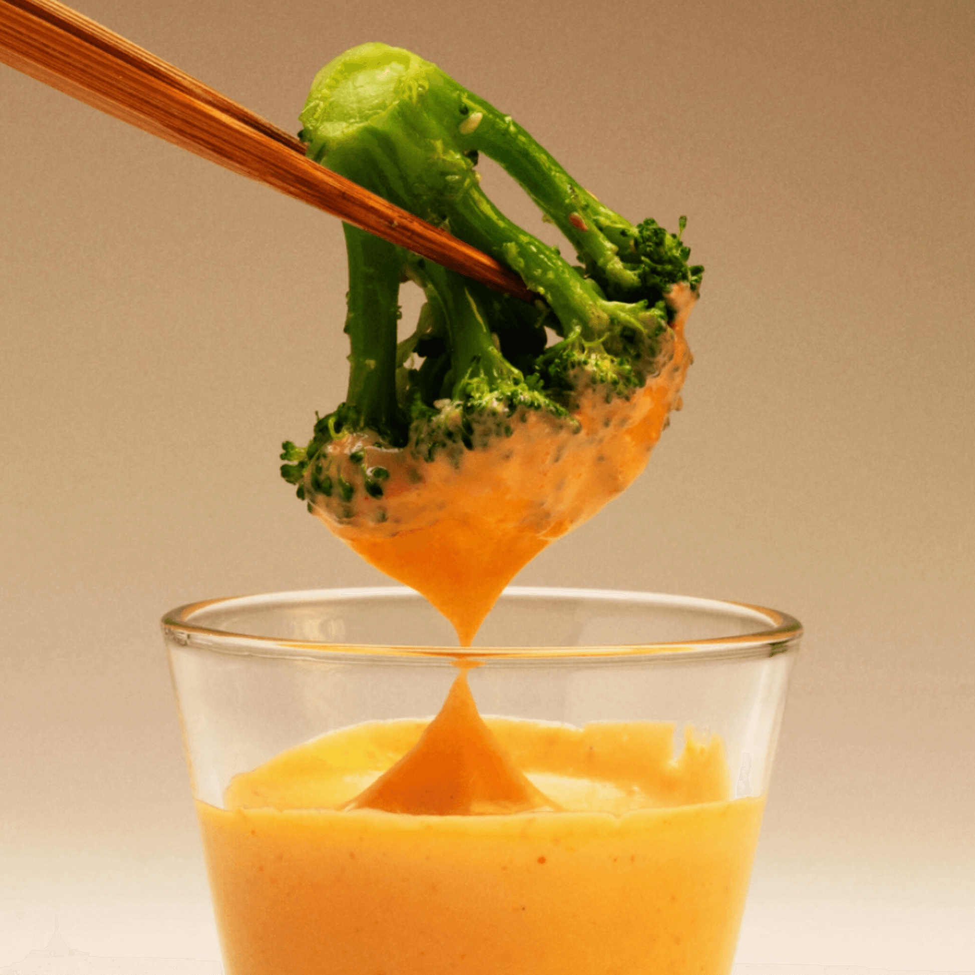 Broccoli being dipped in creamy Japanese spicy mayo, showcasing a healthy snack option.