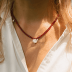 Anni Necklace featuring red coral, blue Japanese seed beads, and a freshwater pearl, elegantly worn on a model.