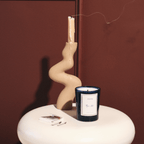 Stylish candle in a modern holder, smoke curling up, against a rich background, perfect for setting an inviting atmosphere.