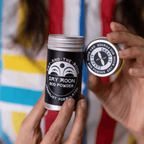 Hands holding Day Moon Bod Powder by Fat and the Moon, a talc-free, herbal body care product.