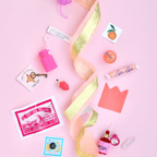 Colorful treasures from the Crystal Ball Surprize Ball, including toys, sweets, and surprises on a pink background.