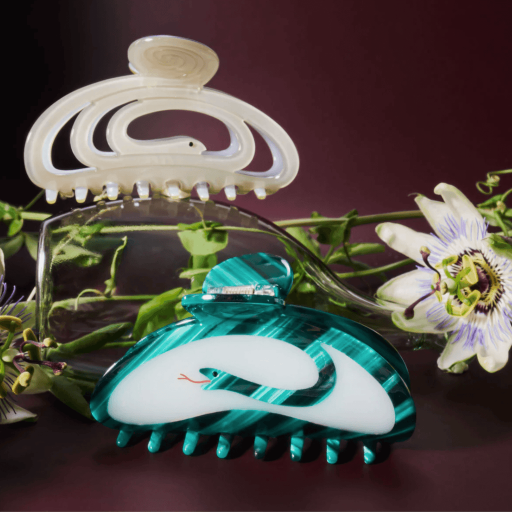 Corra Hair Claw in shimmering pale green, featuring snake design and floral backdrop for a magical hair accessory.