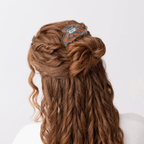 Woman with curly hair wearing a whimsical goldfish hair claw, featuring orange swirls and delicate details.