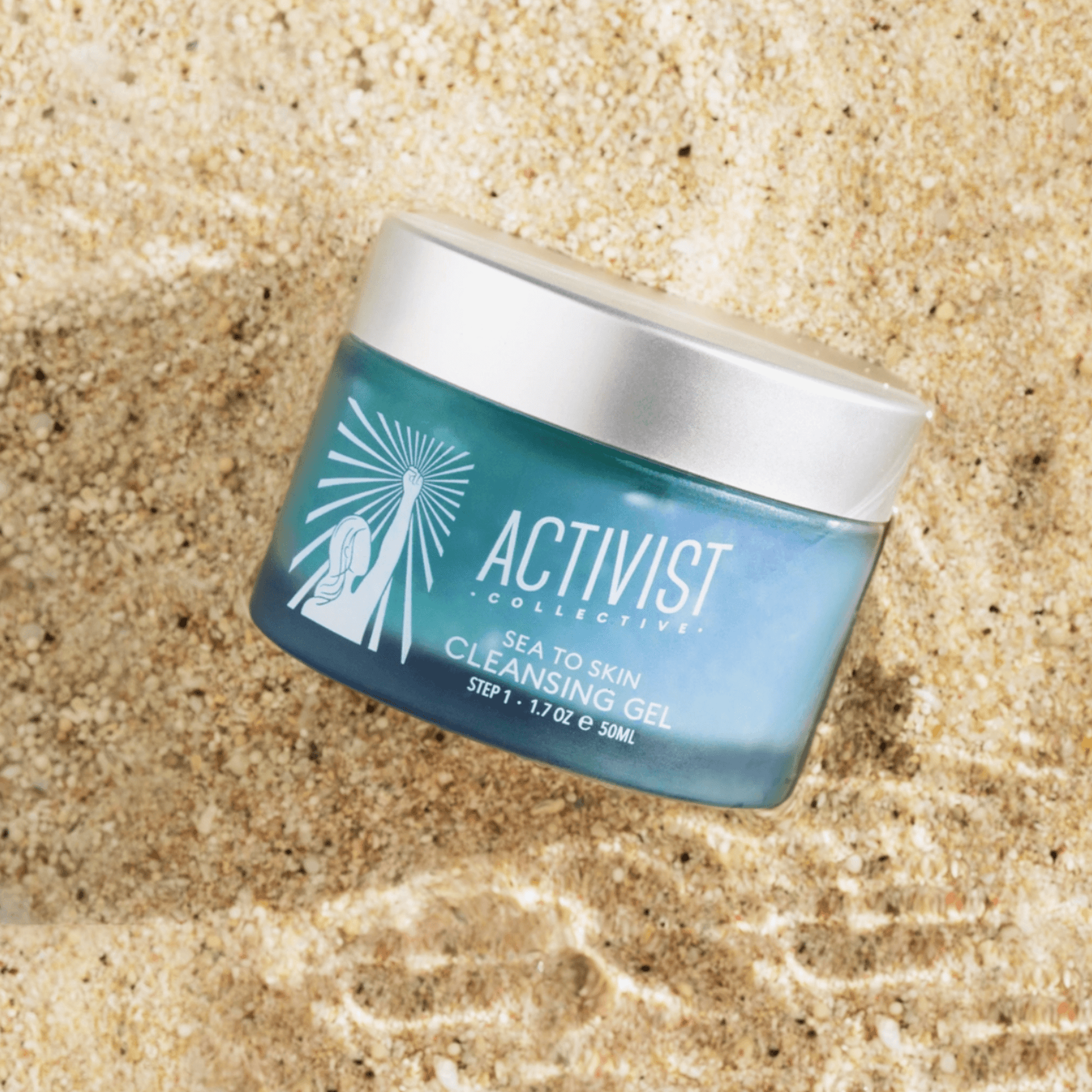 Vivid blue SEA TO SKIN Cleansing Gel in a jar on sandy beach, 50ml, melts makeup and nourishes skin.