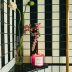Bright pink DE LAS FLORES candle with fresh flowers in a chic bathroom setting, evoking a floral paradise.