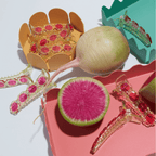 Vibrant watermelon radish alligator hair clips with matching radish, in colorful containers on a white background.