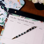 Colorful weekly desk planner featuring a stylish pen, perfect for organizing your schedule with elegance.