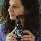 Woman holding Spirit and Salt Mist spray by Fat and the Moon, showcasing natural waves and curls.