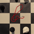 Red KHADI necklace with a freshwater pearl on a chessboard background, symbolizing simplicity and elegance.