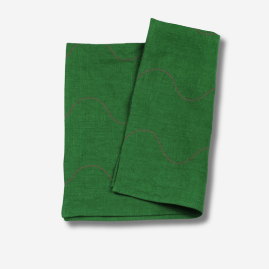 Wavy linen tea towel in vibrant green with pink accents, perfect for kitchen or bath decor.
