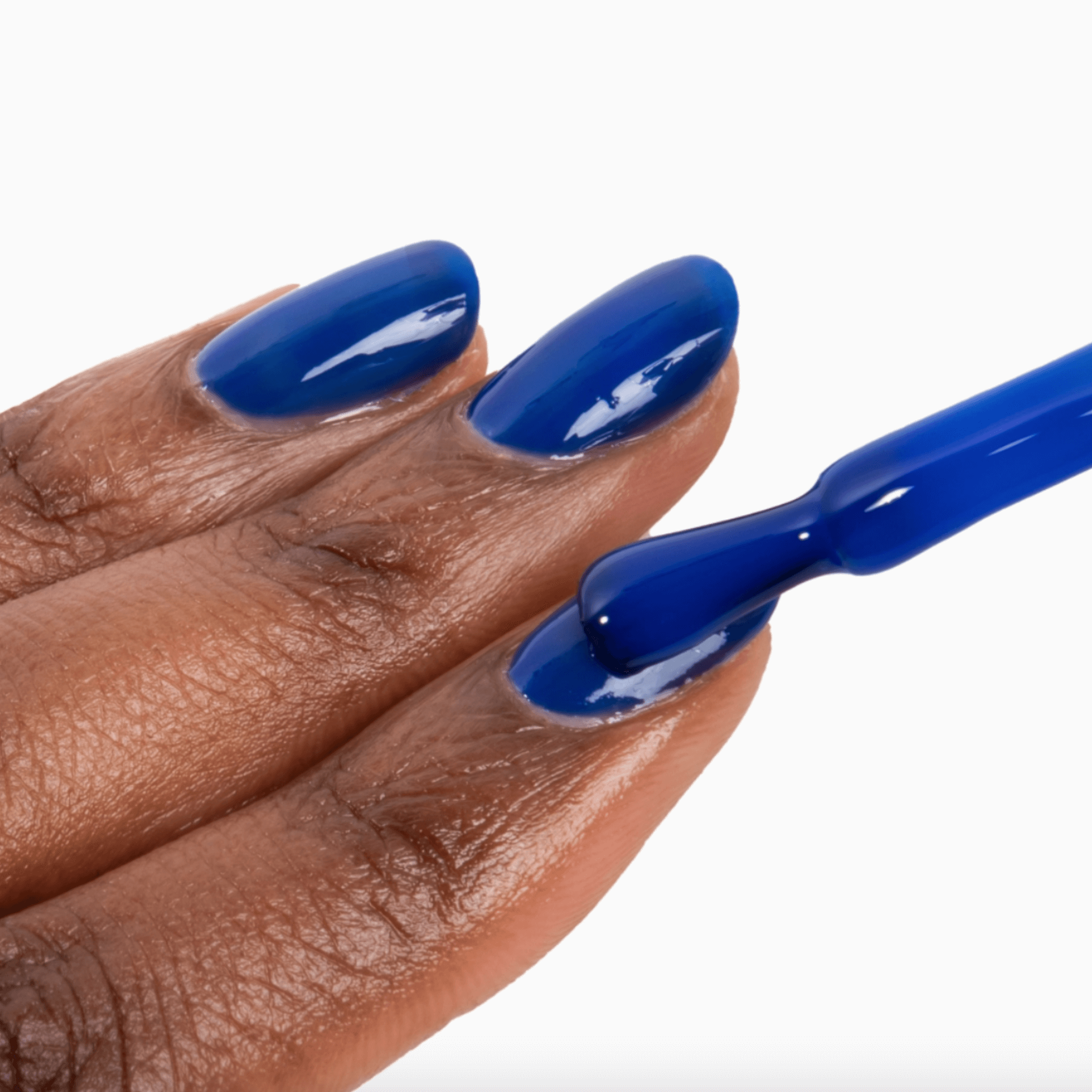 Hand with cobalt blue nails applying Forever Wear Chill Paint for a vibrant, long-lasting manicure.