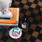 Elegant LA MAISON ROSE candle beside a decorative vase and stylish books on a chic coffee table.