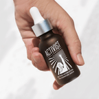 Hand holding ACTIVE HYDRATION VITAMIN C+ ANTIOXIDANT SERUM in a brown glass bottle with a dropper.