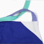 Close-up of a blue linen apron showcasing color-blocked design and contrasting straps.