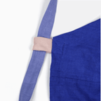 Close-up of blue linen apron strap with contrasting color detail, highlighting the quality craftsmanship and design.