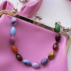 Colorful beaded bag charm featuring marbled resin beads on a pink purse, adding personality to any outfit.