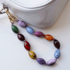 Colorful beaded bag charm with glossy marbled resin beads in vibrant hues, clipped onto a stylish bag.