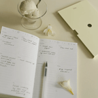 Day Planner open with handwritten notes, a pen, and ice cream in a glass, highlighting daily prioritization.