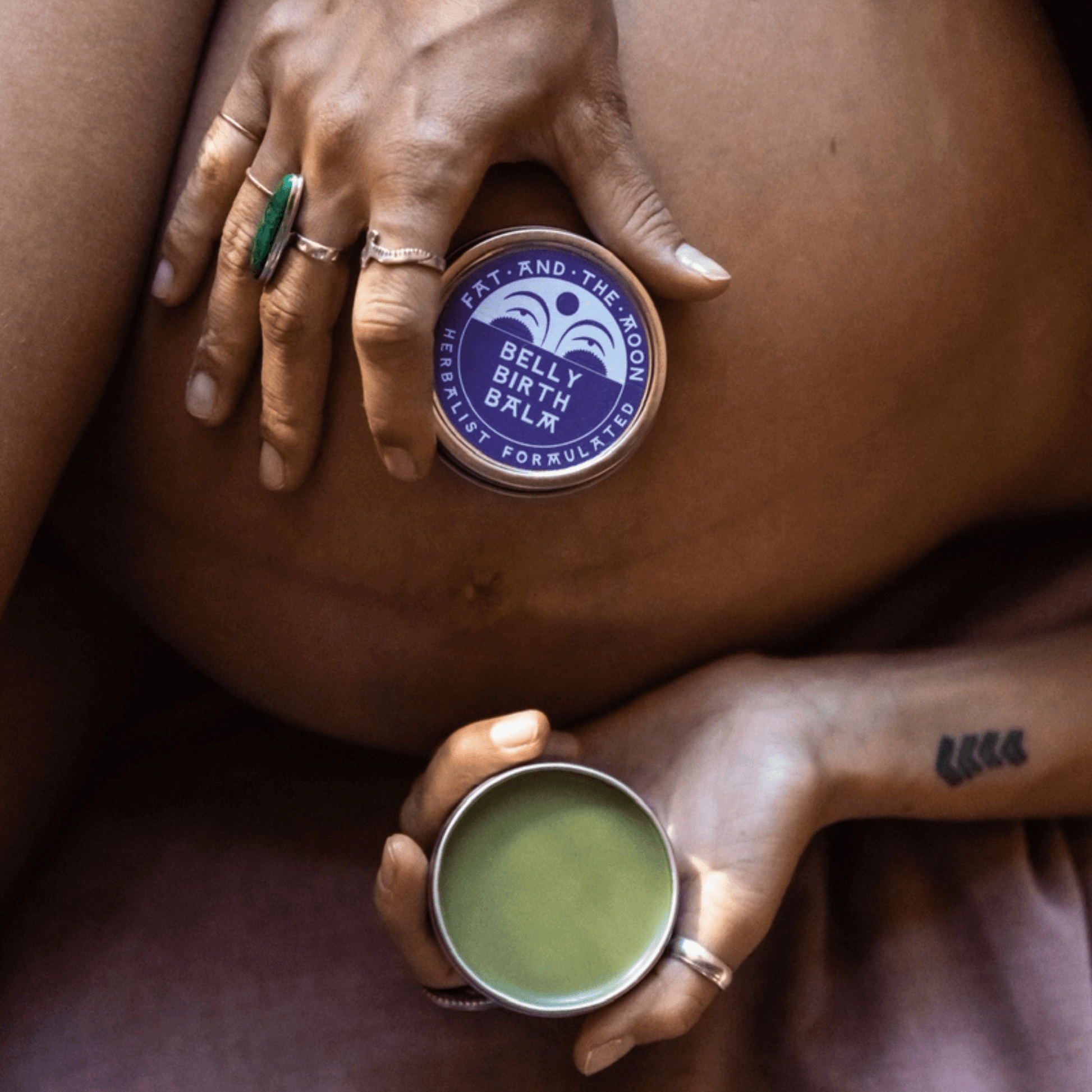 Hands holding Belly Birth Balm on a pregnant belly, promoting healing with herbal ingredients.