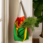 Colorful linen tote bag in green, red, and yellow hanging with fruits and herbs for grocery shopping.