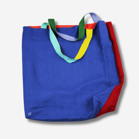 Large linen tote bag in blue and red, featuring vibrant handles and a reversible design, perfect for versatile use.