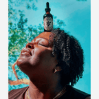 A joyful person with curly hair enjoying tranquility, balancing Wooden Spoon Herbs Tranquility Tonic on their head.