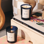 RUE 52 candles on a table beside art books and sculptures, capturing Parisian elegance and rich scents.