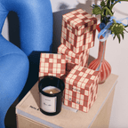 RUE 52 candle beside stylish packaging and fresh flowers, capturing Parisian charm and warm spices.