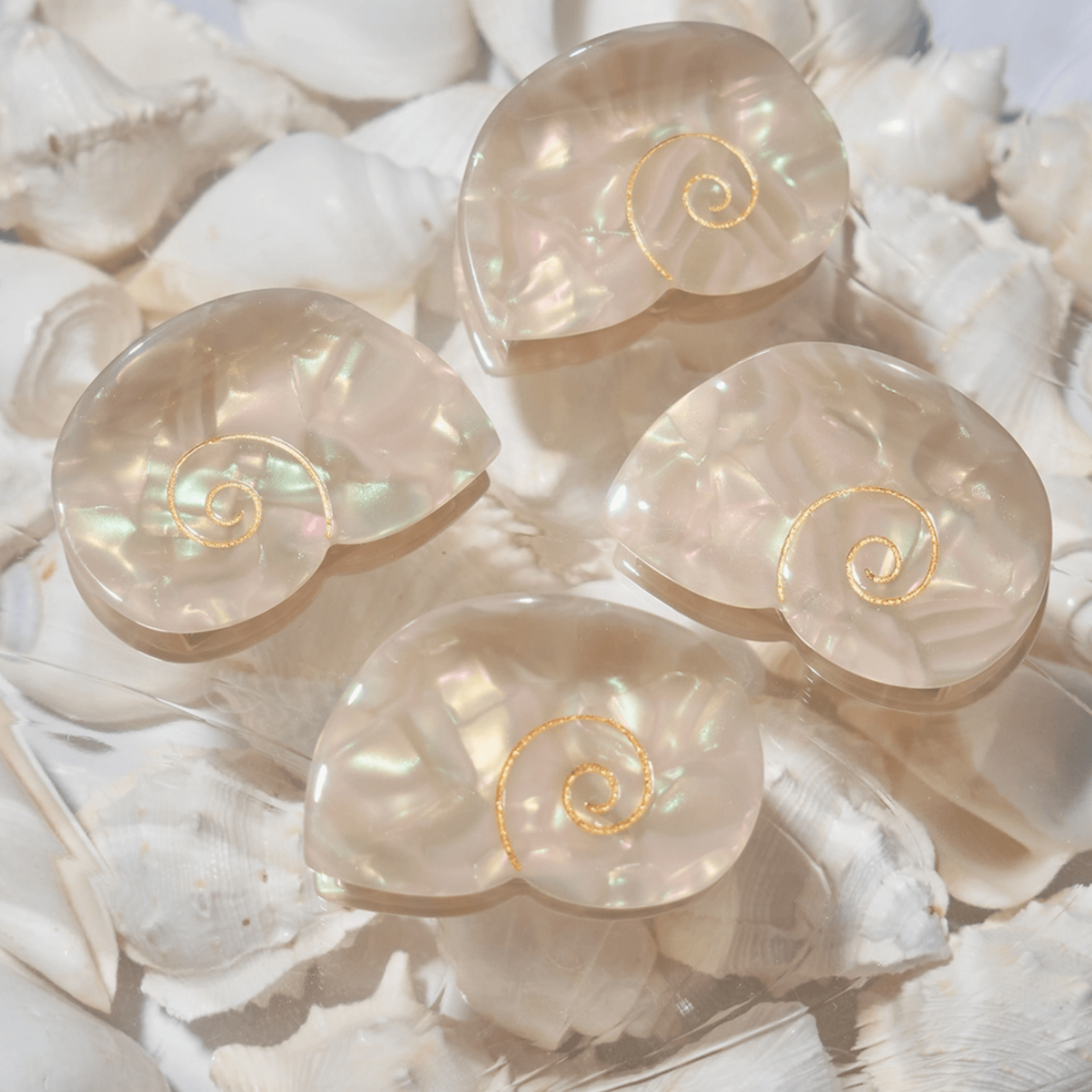 Four shimmering Siren Mini Hair Claws resembling seashells, perfect for adding mermaid energy to any hairstyle.