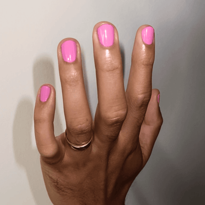 Hand with bubblegum pink nail polish, showcasing a vibrant, playful shade that's vegan and cruelty-free.